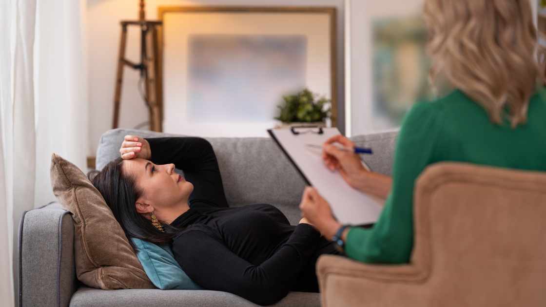 Woman lying on a couch during a therapy session, illustrating how incorporating meditation can enhance relaxation and emotional clarity during therapeutic treatment.