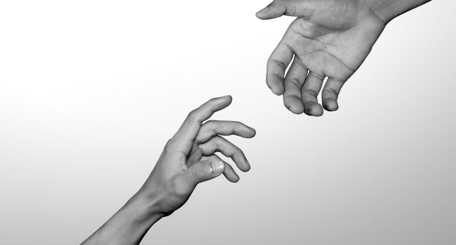 Two hands reaching toward each other, symbolizing support and connection in helping someone with meth addiction.