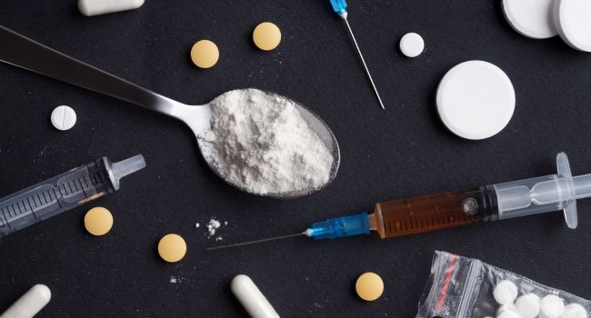 Various drug paraphernalia including pills, syringes, and powdered substance symbolizing meth addiction and treatment needs.