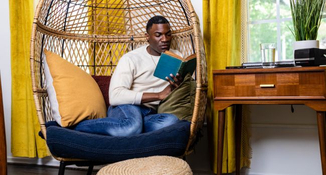 Man relaxing in a cozy chair reading a book, illustrating self-care strategies essential for dual recovery from heroin addiction and depression.