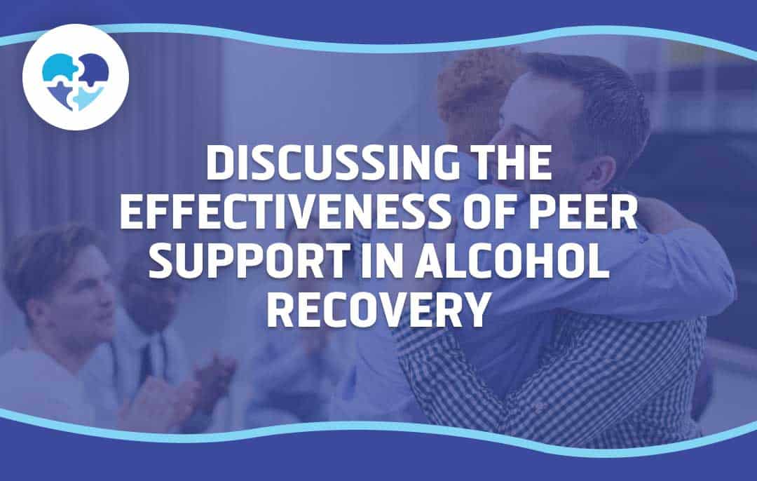 Two people embracing in a supportive setting while others clap, symbolizing the importance of peer support in alcohol recovery. The image highlights emotional connection and shared experiences.