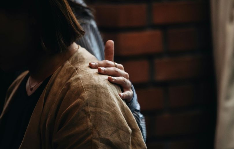 A comforting hand rests on someone's shoulder, symbolizing the emotional support and compassion loved ones can offer in helping someone through addiction recovery with care and understanding.