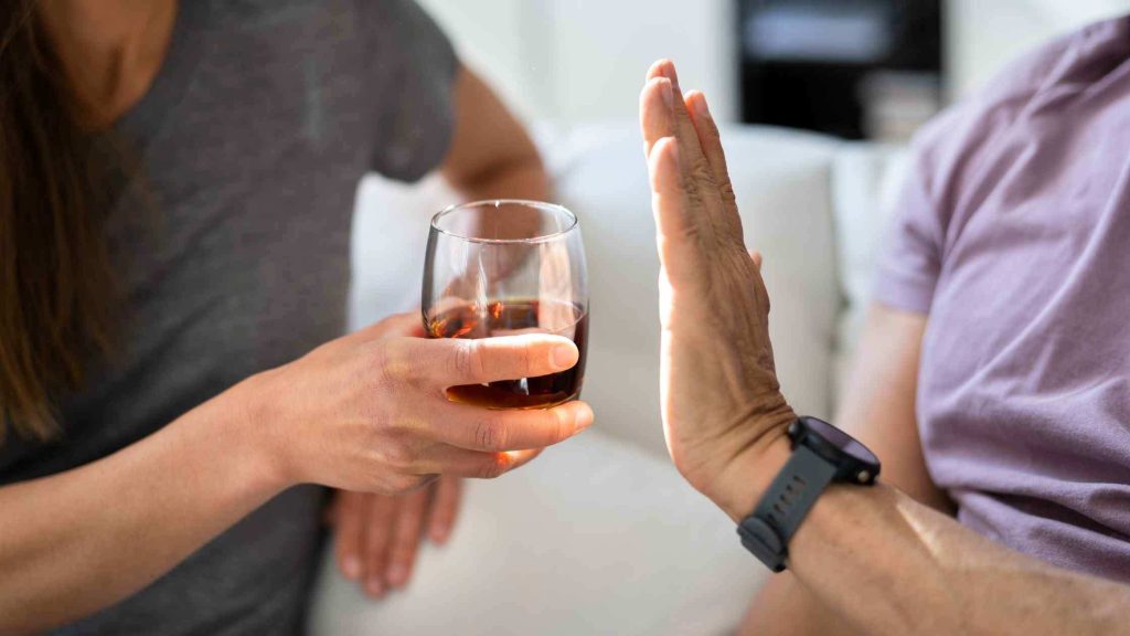 Person refusing a glass of alcohol, symbolizing the importance of stopping alcohol intake well before undergoing surgery.