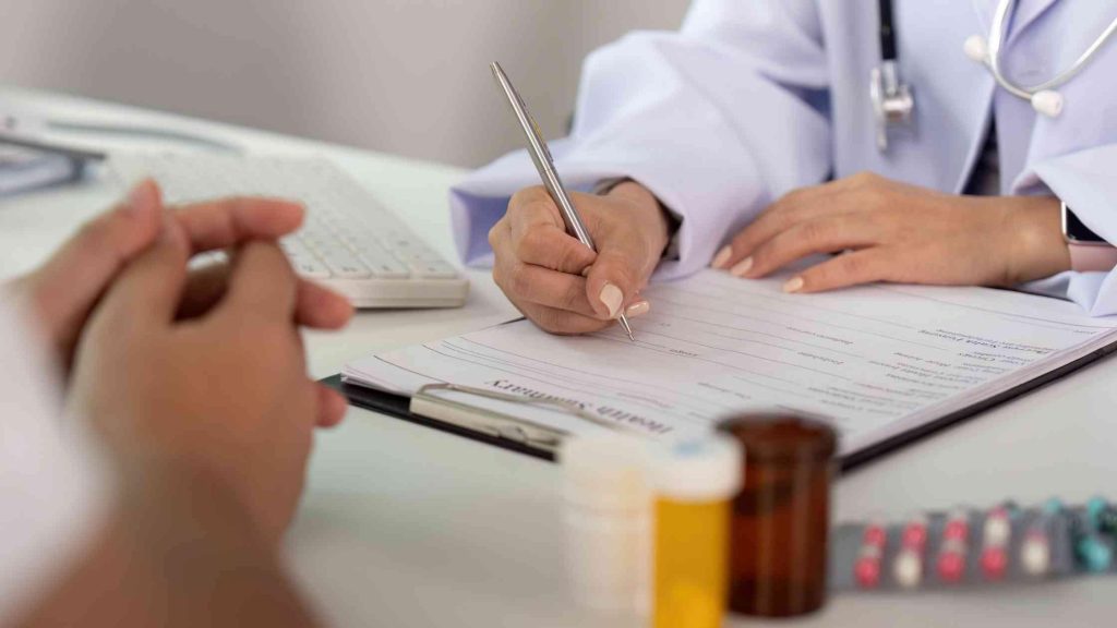 Doctor reviewing medical documents and prescription bottles, representing how to verify your PPO benefits for opioid rehab.